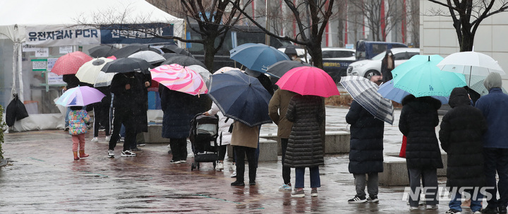 [서울=뉴시스] 조수정 기자 = 토요일인 19일 오전 서울 마포구 서강대역사광장 코로나19 임시선별검사소에서 시민들이 내리는 비에 우산을 들고 검사를 받기 위해 줄서 기다리고 있다. 이날 0시기준 신규확진자수는 38만1454명으로 전날(40만7017명)보다 소폭 감소했다. 2022.03.19. chocrystal@newsis.com