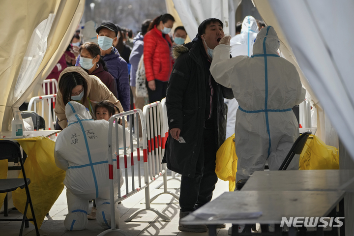 [베이징=AP/뉴시스] 21일 중국 베이징의 한 코로나19 검사소에서 주민들이 코로나19 검사를 받고 있다. 중국에서 오미크론 변이로 인한 코로나19 확산이 이어지자 상하이 디즈니랜드가 임시 폐쇄를 결정했다. 디즈니리조트 측은 "팬데믹 상황을 계속 주시하면서 당국과 협의할 것"이라며 "운영 재개 날짜를 확정하는 대로 알릴 것"이라고 전했다. 2022.03.21.