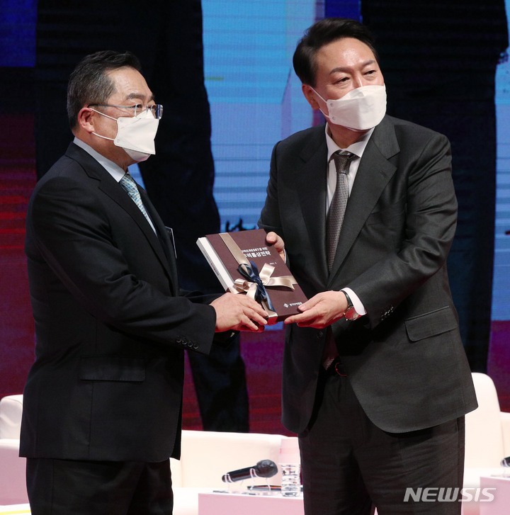 [서울=뉴시스] 인수위사진기자단 = 윤석열 대통령 당선인이 31일 서울 강남구 한국무역협회에서 열린 '청년무역 국가대표와의 만남'에 참석해 구자열 무역협회장에게 정책체언집을 전달 받고 있다. 2022.03.31. photo@newsis.com