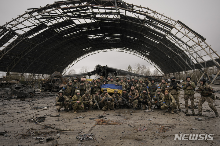 [호스토멜=AP/뉴시스] 지난 2일(현지시각) 우크라이나 호스토멜의 안토노프 공항을 탈환한 우크라이나군 병사들이 러시아군의 공격으로 파괴된 AN-225 므리야 수송기 앞에서 국기를 들고 기념사진을 찍고있다.