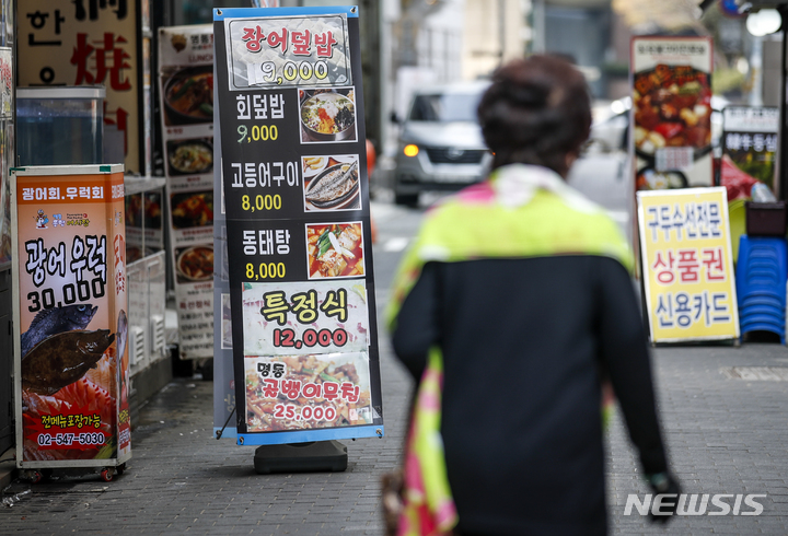 [서울=뉴시스] 정병혁 기자 = 지난 5일 오전 중구 명동거리에서 시민들이 음식점 광고판 앞을 지나가고 있다. 2022.04.05. jhope@newsis.com