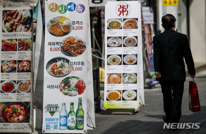 [서울=뉴시스] 정병혁 기자 = 서울 중구 명동거리에서 시민들이 음식점 광고판 앞을 지나가고 있다. 2022.04.05. jhope@newsis.com