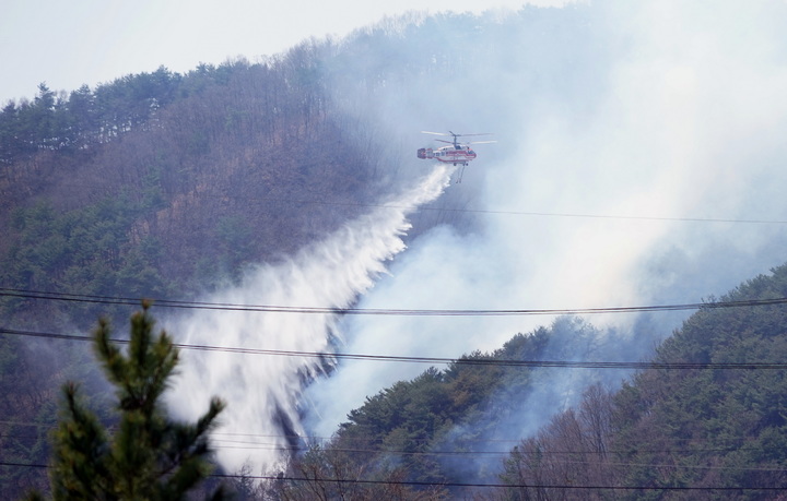 [대전=뉴시스] 11일 강원 양구 일원에 연무가 걷히자 산불진화헬기가 물을 뿌리며 산불을 진화하고 있다.(사진=산림청 제공) *재판매 및 DB 금지