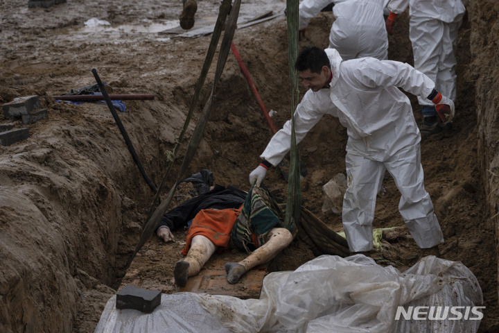 [부차=AP/뉴시스] 10일(현지시간) 우크라이나 키이우 외곽 부차에서 작업자들이 시신의 신원 확인 작업을 위해 집단 매장돼 있던 시신을 꺼내 크레인에 싣고 있다. 2022.04.11.