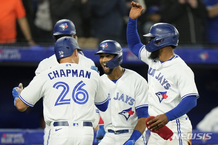 [토론토=AP/뉴시스] 토론토 블루제이스의 맷 채프먼(왼쪽)이 11일(한국시간) 캐나다 토론토 로저스 센터에서 열린 텍사스 레인저스와 2022 MLB 홈경기 1회말에 3점 홈런을 친 뒤 동료들의 축하를 받고 있다. 2022.04.11.