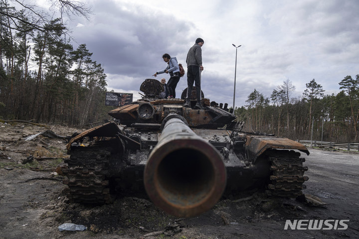 [키이우=AP/뉴시스]지난 11일(현지시간) 우크라이나 키이우 외곽에서 현지 주민들이 교전 중 파괴된 러시아군 전차에 올라가 살피고 있다. 2022.04.12.