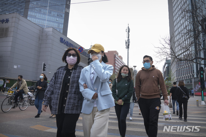 [베이징=AP/뉴시스] 13일(현지시간) 중국 베이징에서 마스크를 쓴 주민들이 교차로를 건너고 있다. 중국 당국이 2년 만에 발생한 최악의 코로나19로 봉쇄를 강화하면서 주요 자동차 회사들과 협력 업체 생산이 타격을 입어 자동차 공급망 혼란이 커지고 있다. 2022.04.13.