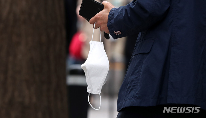 [서울=뉴시스] 추상철 기자 = 정부의 새 거리두기 조정안에 야외 마스크 착용 의무화 일부 해제 방안이 논의되고 있는 14일 오후 서울 도심에서 시민이 마스크를 손에 들고 있다. 2022.04.14. scchoo@newsis.com