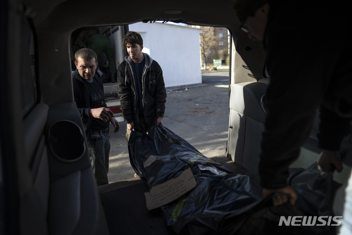 [부차=AP/뉴시스] 미국에서 온 자원봉사자 페이튼 로빈슨(가운데)이 14일(현지시간) 우크라이나 키이우 외곽 부차에서 러시아 군인의 시신을 냉장 컨테이너에 옮기는 작업을 돕고 있다. 2022.04.15.