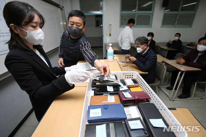 [원주=뉴시스] 김경목 기자 = 17일 오전 국민의힘 강원도당 제8회 전국동시지방선거 공직후보자 기초자격평가(PPAT) 응시자가 강원 원주시 상지대학교 동악관 2고사실에서 시험 전 스마트폰 워치를 제출하고 있다. 2022.04.17. photo31@newsis.com