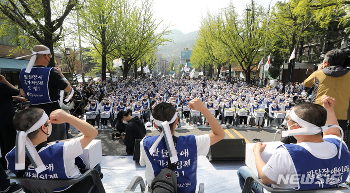 [서울=뉴시스] 김병문 기자 = 발달장애인과 가족 550여 명이 19일 오후 서울 종로구 청와대 인근에서 전국장애인부모연대 주최로 열린 발달장애인 24시간 지원 체계 구축을 위한 1박2일 집중 결의대회에서 단체 삭발을 한 뒤 구호를 외치고 있다. 2022.04.19. dadazon@newsis.com