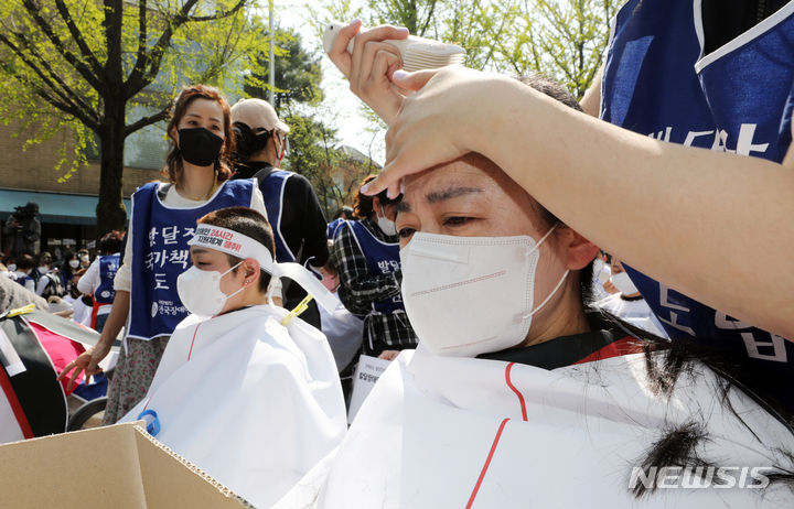 [서울=뉴시스] 김병문 기자 = 발달장애인과 가족 550여 명이 지난 19일 오후 서울 종로구 청와대 인근에서 전국장애인부모연대 주최로 열린 발달장애인 24시간 지원 체계 구축을 위한 1박2일 집중 결의대회에서 단체 삭발을 하고 있다. 2022.04.19. dadazon@newsis.com