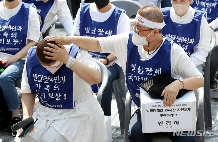 [서울=뉴시스] 김병문 기자 = 발달장애인과 가족 550여 명이 19일 오후 서울 종로구 청와대 인근에서 전국장애인부모연대 주최로 열린 발달장애인 24시간 지원 체계 구축을 위한 1박2일 집중 결의대회에서 단체 삭발을 한 뒤 서로의 머리를 털어주고 있다. 2022.04.19. dadazon@newsis.com