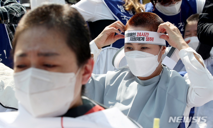 [서울=뉴시스] 김병문 기자 = 발달장애인과 가족 550여 명이 19일 오후 서울 종로구 청와대 인근에서 전국장애인부모연대 주최로 열린 발달장애인 24시간 지원 체계 구축을 위한 1박2일 집중 결의대회에서 단체 삭발을 하고 있다. 2022.04.19. dadazon@newsis.com