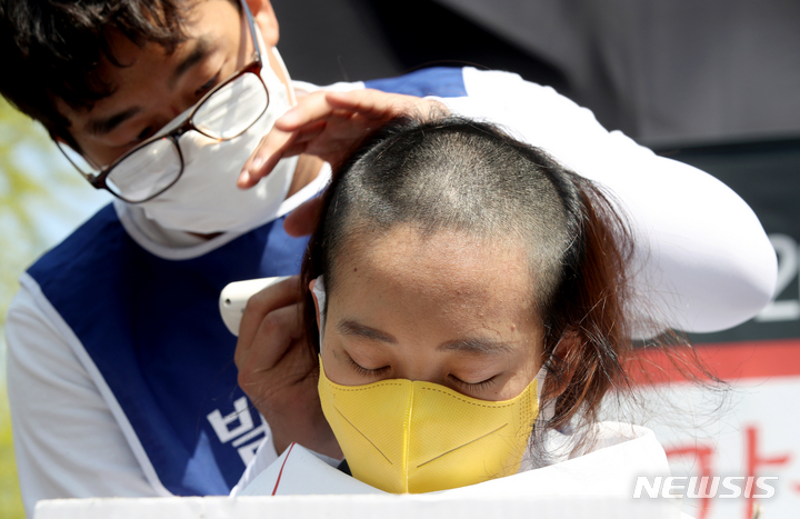 [서울=뉴시스] 김병문 기자 = 장혜영 정의당 의원이 19일 오후 서울 종로구 청와대 인근에서 전국장애인부모연대 주최로 열린 발달장애인 24시간 지원 체계 구축을 위한 1박2일 집중 결의대회에서 단체 삭발에 동참하고 있다. 2022.04.19. dadazon@newsis.com