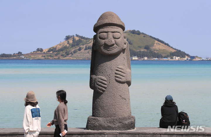 [제주=뉴시스] 우장호 기자 = 맑은 날씨를 보이는 20일 오전 제주시 한림읍 금능해수욕장에 서 있는 돌하르방이 사회적 거리두기 기간 동안 쓰고 있던 마스크를 벗어 신비한 미소를 보이고 있다. 2022.04.20. woo1223@newsis.com