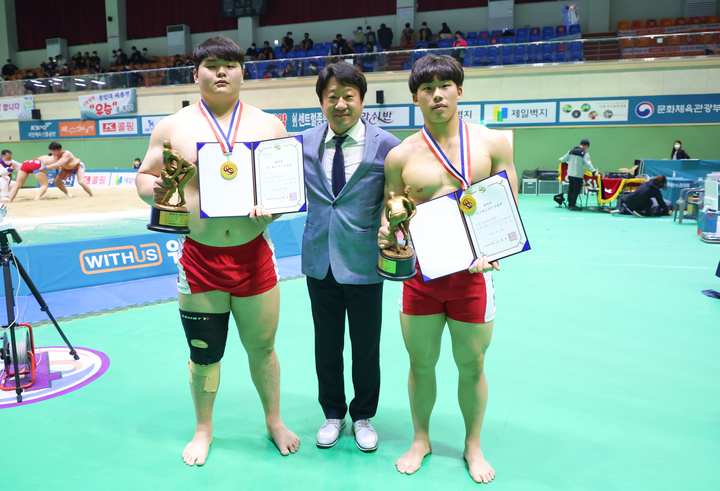 [울산=뉴시스] 구미현 기자 = 울산대학교 씨름부 라현민(청장급·오른쪽)과 김민재(장사급·왼쪽)가 제76회 전국씨름선수권대회 선수권부에서 개인전 우승을 일군 뒤 주명찬 감독(가운데)과 기념 포즈를 취하고 있다. 2022.04.23. (사진=울산대 제공) *재판매 및 DB 금지