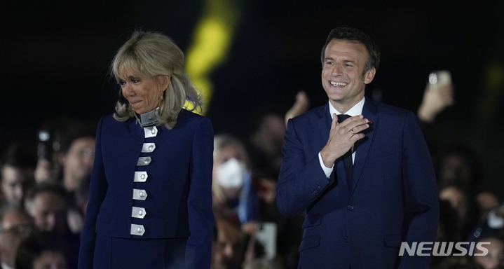 [파리=AP/뉴시스] 에마뉘엘 마크롱(오른쪽) 프랑스 대통령이 24일(현지시간) 대선 결선 투표에서 승리한 후 부인 브리지트 여사와 샹드마르스 광장을 찾아 지지자들을 향해 인사하고 있다. 마크롱 대통령의 연임으로 지난 20년간 이어졌던 프랑스의 ‘현직 대통령 재선 실패’ 징크스가 깨졌다. 2022.04.25.