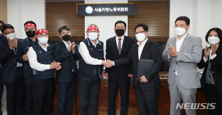 [서울=뉴시스] 조수정 기자 = 조장우(가운데 오른쪽) 서울시버스운송사업조합 이사장과 박점곤(가운데 왼쪽) 서울시버스노동조합 위원장이 지난해 4월 26일 새벽 서울 영등포구 서울지방노동위원회에서 열린 사후조정에서 협상을 타결, 조정안에 서명한 뒤 조정위원들과 기념촬영 하고 있다. 2022.04.26. chocrystal@newsis.com