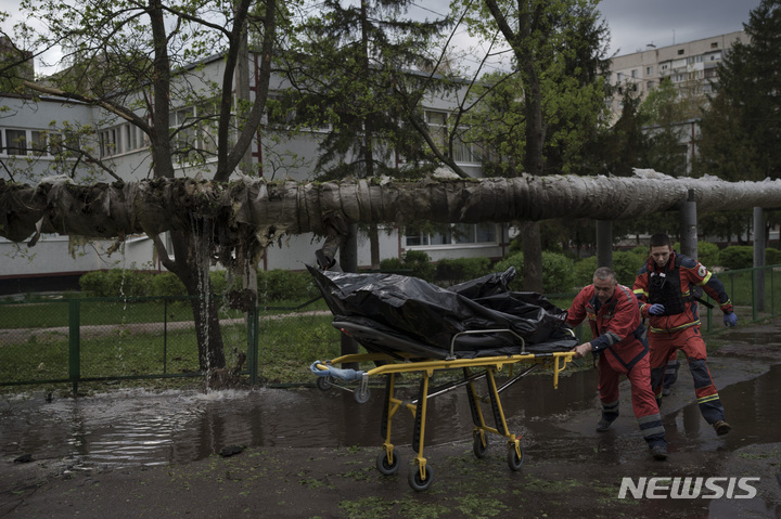 [하르키우=AP/뉴시스] 27일(현지시간) 우크라이나 하르키우에서 긴급구조대원들이 러시아군의 포격으로 숨진 희생자의 시신을 옮기고 있다. 2022.04.28.