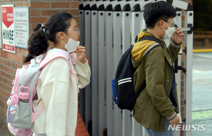 [광주=뉴시스] 류형근 기자 = 실외에서 마스크를 착용하지 않아도 되는 2일 오전 광주 남구 한 초등학교 교문에서 일명 '턱스크'를 한채 등교했던 학생들이 마스크를 다시 쓰고 있다. 2022.05.02. hgryu77@newsis.com