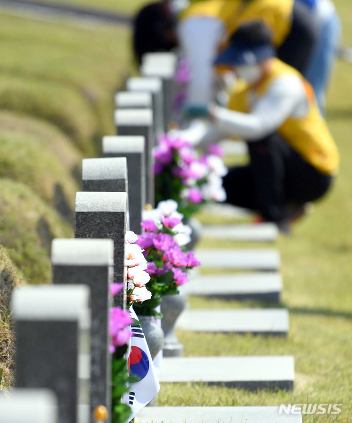 [광주=뉴시스] 류형근 기자 = 5·18민주화운동 42주기를 2주 앞둔 4일 오전 광주 북구 운정동 국립5·18민주묘지에서 대한적십자사 광주전남지사 적십자봉사원과 RCY단원들이 묘비 닦기·조화교체 활동을 하고 있다. 2022.05.04. hgryu77@newsis.com