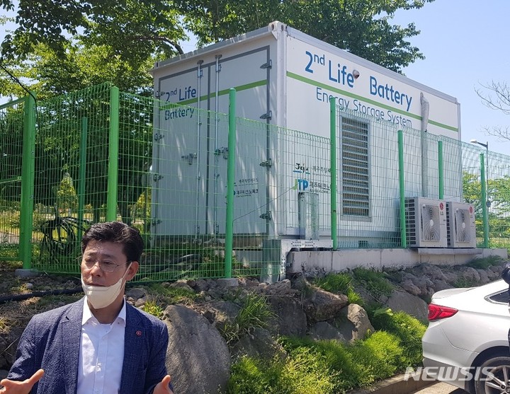 [제주=뉴시스]박정규 기자=이동훈 제주테크노파크 에너지융합센터 활용기술개발팀장이 지난 4일 기자들과 만나 전기차 사용 후 배터리 재사용에 대해 설명하고 있다. 뒤에 보이는 구조물은 전기차배터리산업화센터에서 재사용한 폐배터리로 만든 대용량 에너지저장장치(ESS). 2022.5.6 photo@newsis.com 