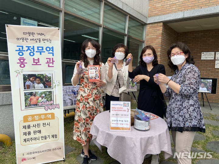 [전주=뉴시스]윤난슬 기자 = 공정무역 홍보관에 참여한 시민들이 공정무역 지지 홍보물과 공정무역 계피주머니 만들기 체험 후 웃고 있다.(사진=전북소비자정보센터 제공) 