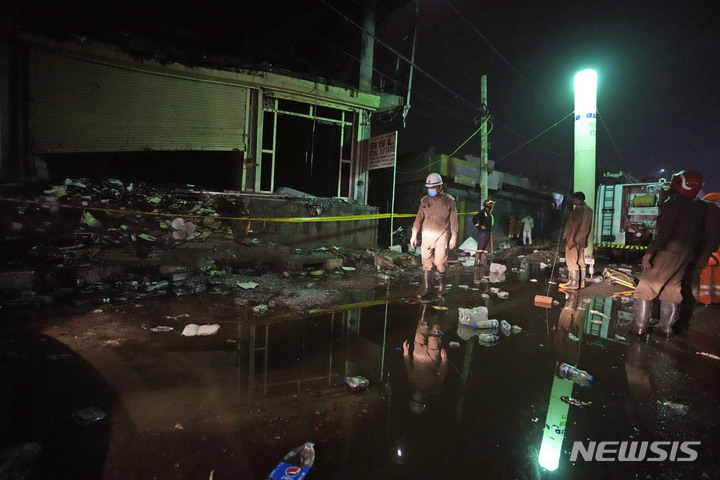 [뉴델리=AP/뉴시스] 14일(현지시간) 인도 뉴델리에서 소방대원들이 상가 화재 현장을 둘러보고 있다. 전날 저녁 뉴델리 서부에 있는 한 4층 상업용 건물에서 큰 불이나 최소 27명이 숨지고 약 40명이 다쳤다. 2022.05.14 