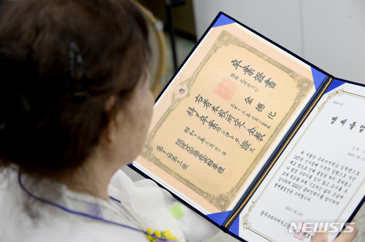 [광주=뉴시스] 김혜인 기자 = 14일 오전 광주 남구 양림동 수피아여자고등학교 강당 지하 1층에서 85년 만에 모교를 찾은 김덕화 할머니가 명예졸업장을 바라보고 있다. 2022.05.14. hyein0342@newsis.com