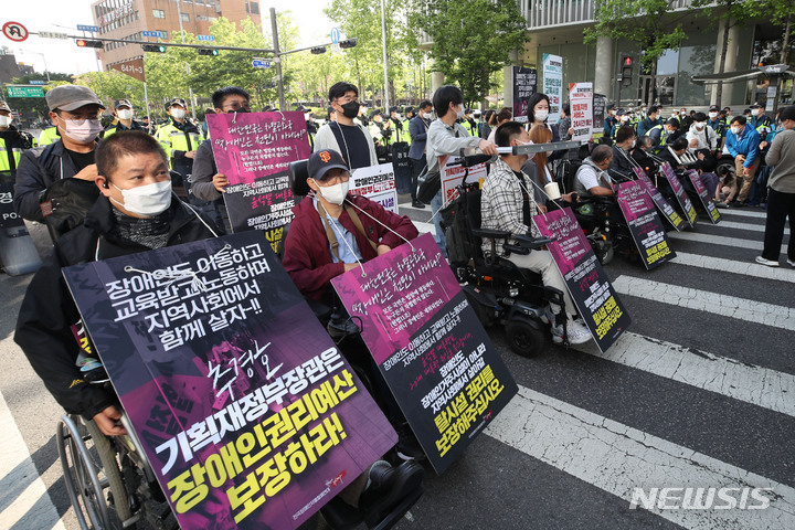 [서울=뉴시스] 권창회 기자 = 전국장애인자별철폐연대 회원들이 16일 오전 서울 용산구 신용산역 인근에서 장애인권리예산 22년 추경반영 촉구 출근길 행진 중 횡단보도를 막고 시위를 하고 있다. 2022.05.16. kch0523@newsis.com