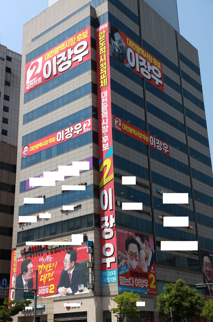 [대전=뉴시스] 조명휘 기자 = 허태정 더불어민주당 대전시장후보 선대위가 17일 임금 왕(王)’자 형상을 하고 있다고 지적한 이장우 국민의힘 후보의 선거사무실이 위치한 건물에 내걸린 홍보 현수막. 2022.05.17. photo@newsis.com *재판매 및 DB 금지