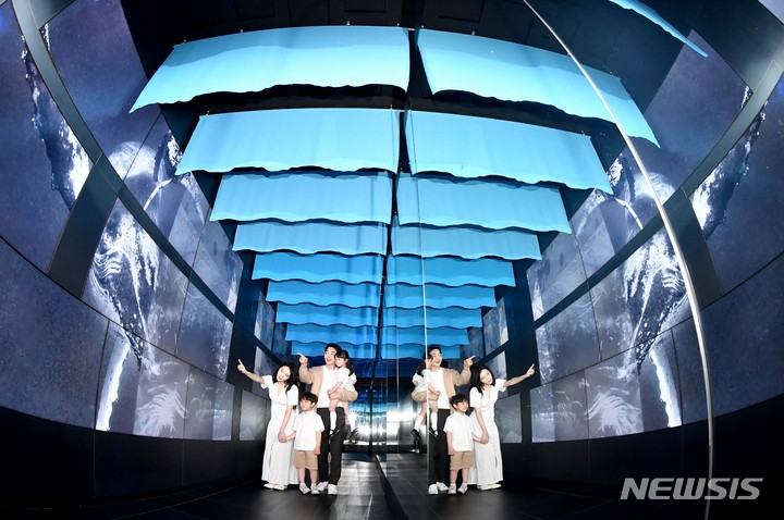 [서울=뉴시스] 권창회 기자 = 17일 오전 서울 송파구 롯데월드타워 서울스카이를 찾은 가족이 미디어아트 특별전 '나는 고래'의 미디어터널을 지나고 있다. (공동취재사진) 2022.05.17. photo@newsis.com