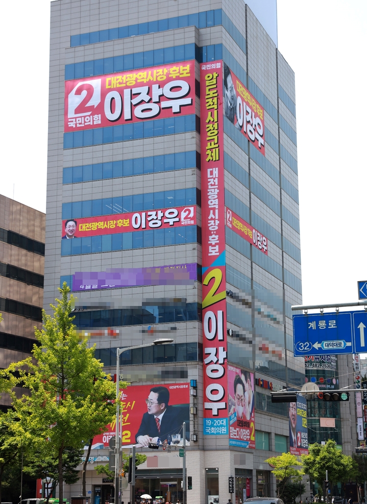 [대전=뉴시스] 조명휘 기자 = 허태정 더불어민주당 대전시장후보 선대위가 17일 임금 왕(王)’자 형상을 하고 있다고 지적한 이장우 국민의힘 후보의 선거사무실 건물에 내걸린 홍보 현수막. 2022.05.17. photo@newsis.com *재판매 및 DB 금지
