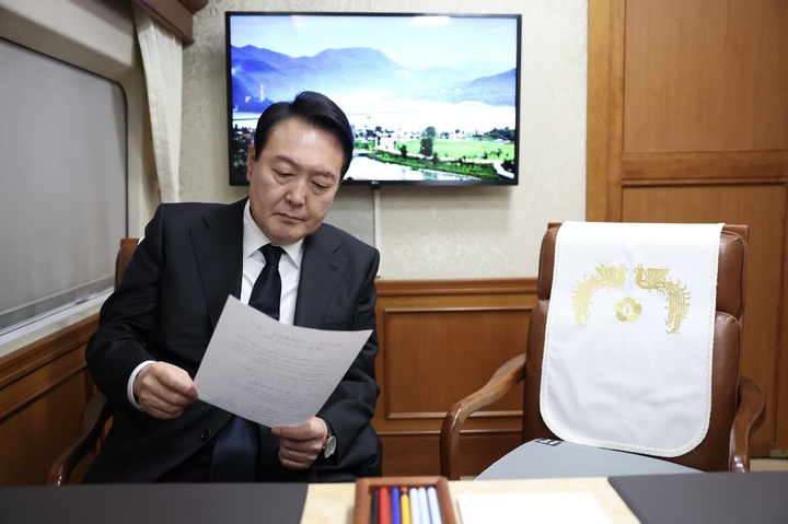 [서울=뉴시스] 윤석열 대통령이 18일 광주송정역으로 향하는 KTX 특별열차에서 제42주년 5·18 민주화운동 기념식 관련 자료를 살펴보고 있다. (사진=대통령실 제공) 2022.05.18. photo@newsis.com *재판매 및 DB 금지