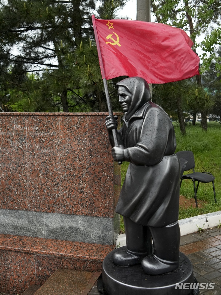 [마리우폴=AP/뉴시스] 18일(현지시간) 우크라이나 동부 도네츠크인민공화국(DPR) 산하 마리우폴에 구 소련의 붉은 깃발을 든 우크라이나 여성 동상이 서 있다. 마리우폴을 완전 장악한 러시아군은 아조우스탈 제철소 우크라이나 군인들이 계속해서 투항하고 있다고 발표했다. 2022.05.19.