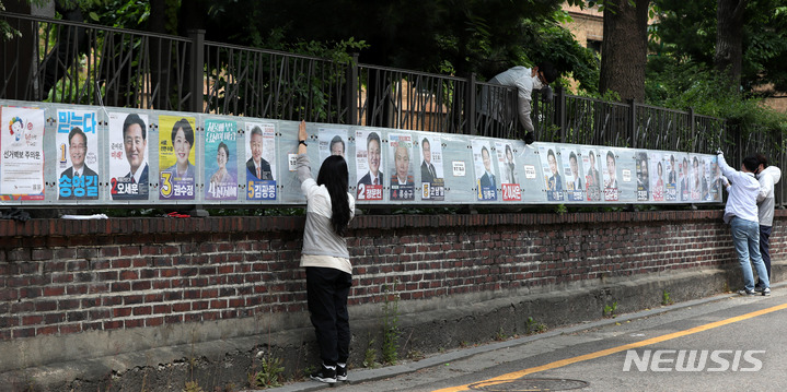 [서울=뉴시스] 추상철 기자 = 제8회 전국동시지방선거 공식 선거운동이 시작된 19일 오후 서울 종로구 대학로에서 선거관계자가 선거벽보를 부착하고 있다. 2022.05.19. scchoo@newsis.com