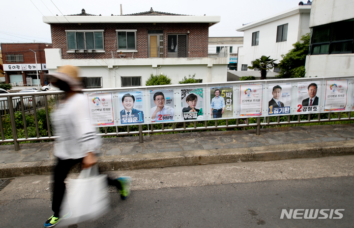[제주=뉴시스] 우장호 기자 = 제8회 전국동시지방선거 공식 선거운동이 시작된 19일 오후 제주시 이도2동 주택가에서 한 유권자가 선거벽보 앞을 지나고 있다. 2022.05.19. woo1223@newsis.com