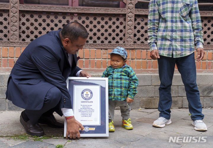 [카트만두=AP/뉴시스] 24일(현지시간) 네팔 카트만두에서 도르 바하두르 카판지(Dor Bahadur Khapangi)가 기네스 세계 기록 인증서를 받고 있다. 2004년 11월 14일생인 카판지는 신장 73.43㎝로, 세계에서 가장 작은 청소년으로 인정받았다. 2022.05.25.