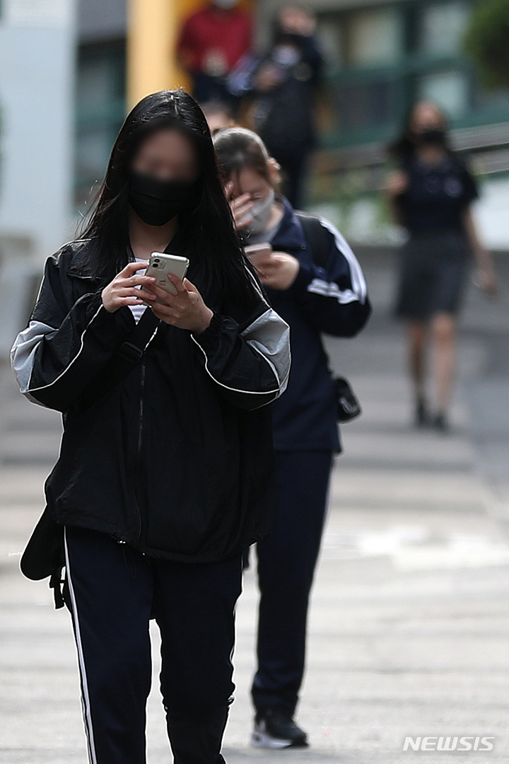 [서울=뉴시스] 백동현 기자 = 25일 오후 서울 시내 한 중학교 앞에서 학생들이 스마트폰을 보면서 하교하고 있다. 사진은 기사 내용과 직접적 연관 없음. 2022.05.25. livertrent@newsis.com