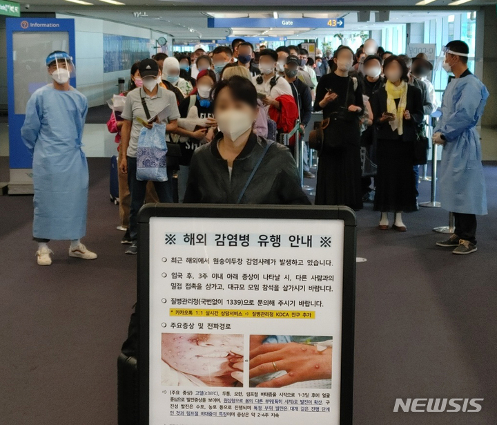 [인천공항=뉴시스] 최동준 기자 = 지난 27일 오전 인천국제공항 제1여객터미널 입국장에서 독일 프랑크푸르트와 우즈베키스탄발 탑승객들이 검역을 받기 위해 대기하고 있는 가운데 원숭이두창 안내문이 게시되어 있다. (공동취재사진) 2022.05.27. photo@newsis.com