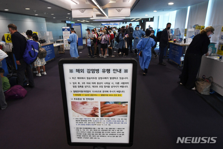 [인천공항=뉴시스] 최동준 기자 = 지난 27일 오전 인천국제공항 제1여객터미널 입국장에서 독일 프랑크푸르트와 우즈베키스탄발 탑승객들이 검역을 받기 위해 대기하고 있는 가운데 원숭이 두창 안내문이 게시되어 있다. (공동취재사진) 2022.05.27. photo@newsis.com