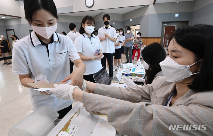 [수원=뉴시스] 김종택기자 = 제8회 전국동시지방선거 사전투표가 시작된 27일 오후 경기도 수원시 연무동 행정복지센터에 마련된 사전투표소에서 삼일공업고등학교 3학년인 만 18세 학생 유권자들이 첫 투표를 하기 위해 투표용지를 배부받고 있다. 2022.05.27. jtk@newsis.com