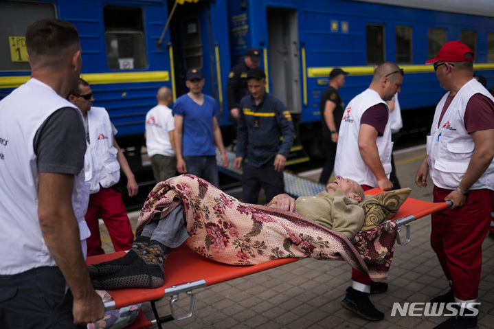 [포크로우스크=AP/뉴시스] 29일(현지시간) 우크라이나 동부 포크로우스크 기차역에서 구급대가 '국경없는의사회'(MSF)가 운영하는 의료 열차에 환자를 싣고 있다. 의료 장비를 갖춘 이 열차는 포화상태인 최전방 병원의 환자들을 우크라이나 서부 의료 시설로 실어 나른다. 2022.05.30.