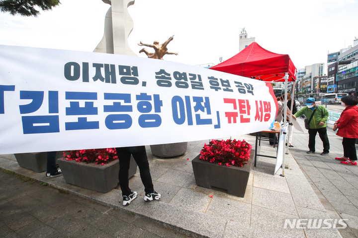 [제주=뉴시스] 우장호 기자 = 30일 오후 제주시청 조형물 앞에서 열린 '김포공항 이전 폐지 규탄 서명운동'에 시민들이 공항 이전 반대의견을 나타내는 스티커를 부착하고 있다. 2022.05.30. woo1223@newsis.com