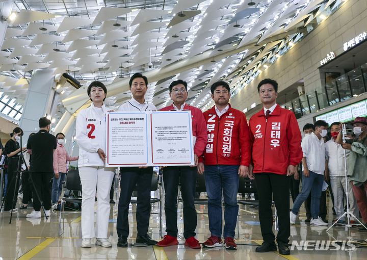 [서울=뉴시스] 국회사진기자단 = 김은혜(왼쪽부터) 국민의힘 경기도지사 후보, 오세훈 서울시장 후보, 허향진 제주도지사 후보, 부상일 제주을 국회의원 보궐선거 후보, 김태우 강서구청장 후보가 지난 30일 서울 강서구 김포공항 국내선 청사에서 김포공항 이전 저지를 위한 공동 기자회견을 마친 뒤 연대협약서를 취재진에게 보여주고 있다. 2022.05.30. photo@newsis.com