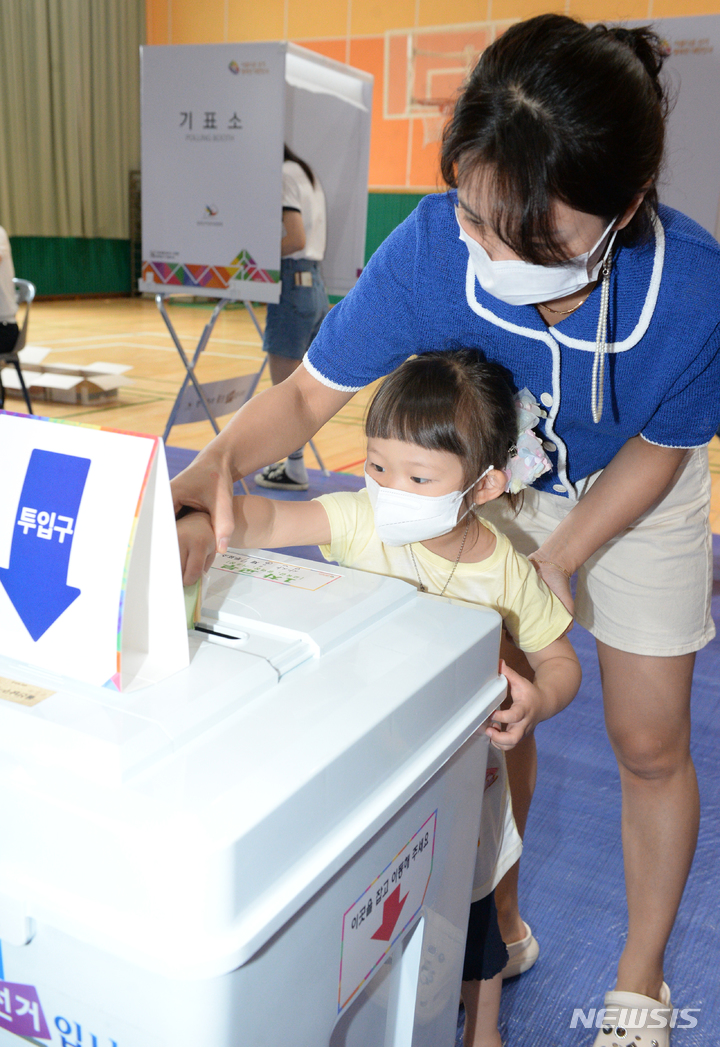 [울산=뉴시스] 배병수 기자 = 제8회 전국동시지방선거일인 1일 오전 울산 남구 삼산초등학교에 마련된 삼산제7투표소에서 아이가 엄마와 함께 투표용지를 투표함에 넣고 있다. 2022.06.01. bbs@newsis.com