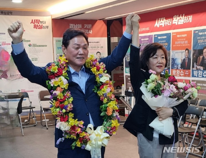 [창원=뉴시스] 홍정명 기자= 박완수 국민의힘 경남도지사 후보가 1일 밤 당선이 확실시 되자 축하 꽃다발을 목에 걸고 부인 차경애 여사와 기념촬영을 하고 있다.(사진=박완수 선거캠프 제공) 2022.06.02. photo@newsis.com