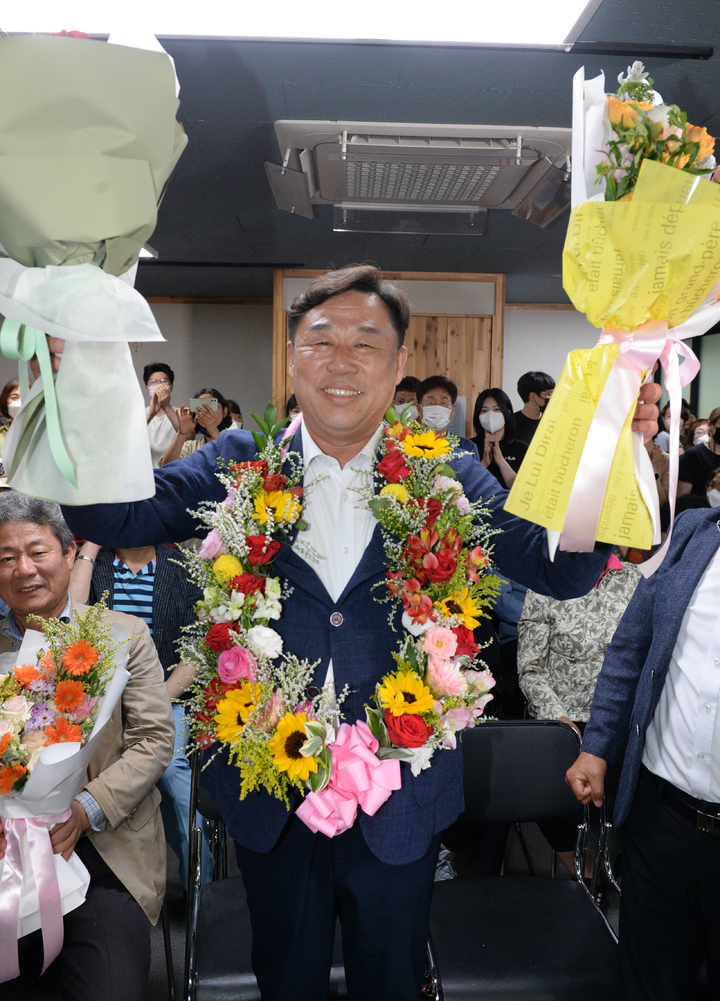 [울산=뉴시스] 배병수 기자 = 제8회 전국동시지방선거에서 진보당 김종훈 동구청장 후보가 자신의 선거사무소에서 당선이 확실시되자 꽃목걸이와 꽃다발을 들고 환하게 웃고 있다. 2022.06.02. bbs@newsis.com