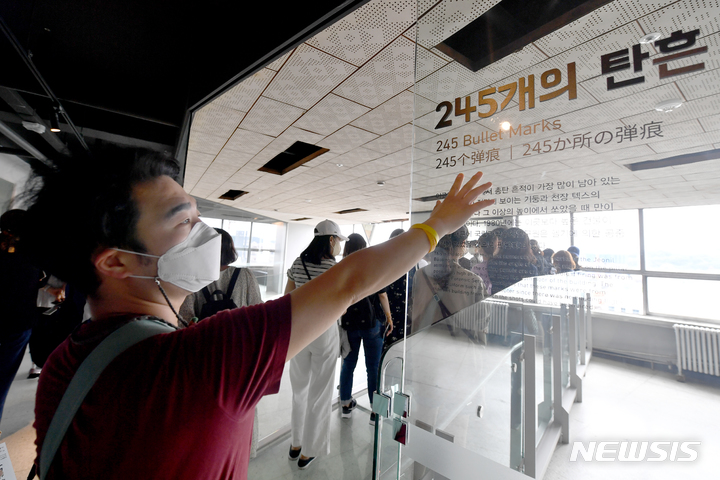 [광주=뉴시스] 이영주 기자 = 5일 오전 광주 동구 전일빌딩245에서 5·18기념재단의 '오월학교' 연수에 참여한 경기도 지역 교사가 헬기 사격 흔적을 가리키는 안내문을 손으로 훑고 있다. 2022.06.05. leeyj2578@newsis.com